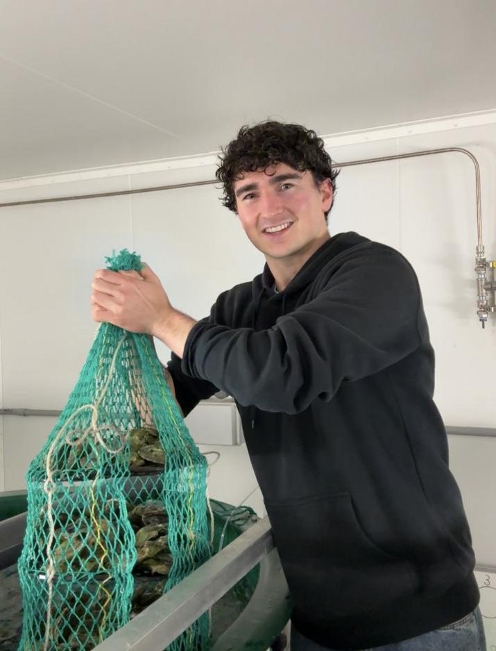 Keegan Jalbert, founder of AccessFlora, lifting a bag of oysters raised on AccessFlora feed